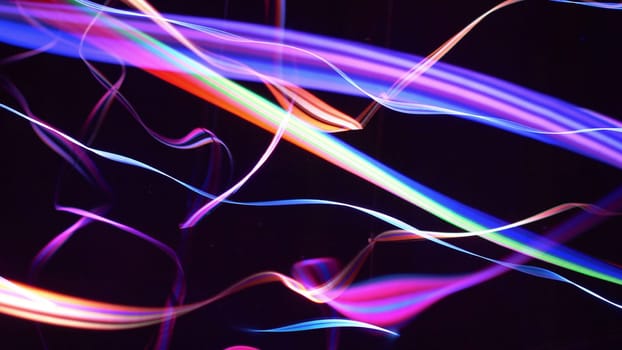Colorful fiber strings in motion against black background