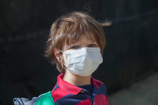 6 years little boy wearing a face mask straight into the camera. He has a stiff gesture