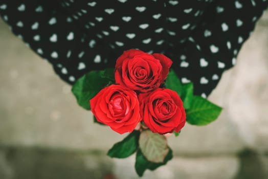 Woman in coat holding red roses in her hands. Retro style.