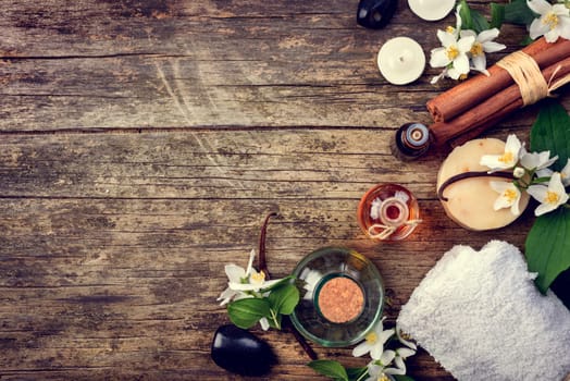 Essential oils with jasmine, cinnamon and vanilla on rustic wooden table, retor style image.