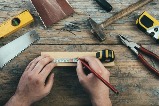 Male hands working on carpenter's desk and working tools.