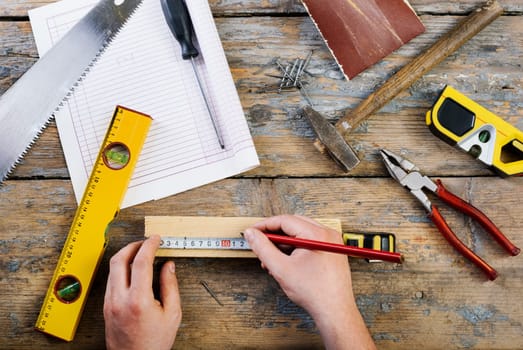 Male hands working on carpenter's desk and working tools.