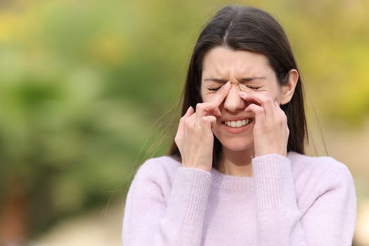 Teen scratching itchy eyes complaining outdoors in a park