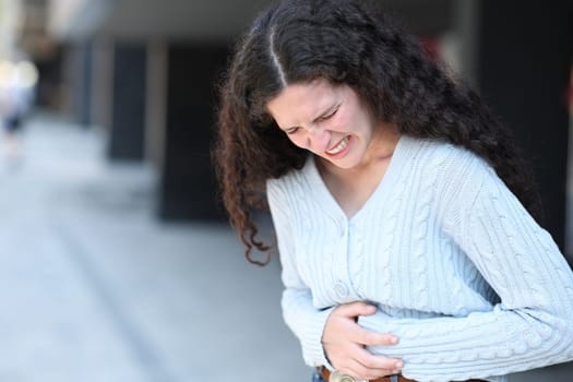 Stressed woman complaining in the street suffering belly ache