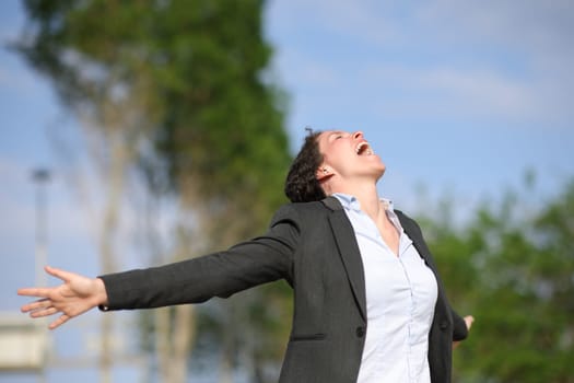Excited executive screaming and outstretching arms in a park