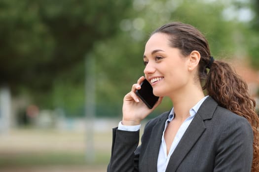 Happy businesswoman talking on cell phone walking in a park