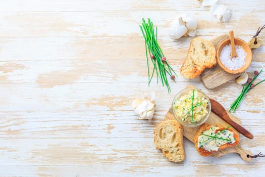 Homemade garlic butter with herbs and chives and fresh roasted baguette with salt and copy space