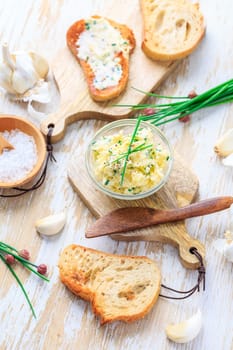 Homemade garlic butter with herbs and chives and fresh roasted baguette with salt