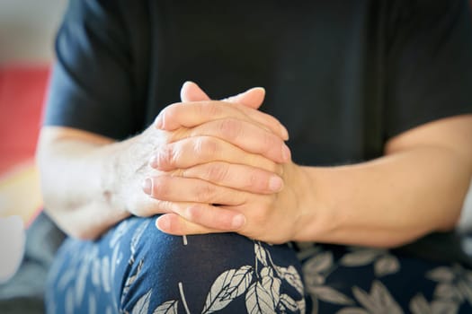 Woman with folded hands sits relaxed and listens to conversation