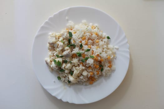 dish with rice, green onions, corn and fish on a plate overhead shot