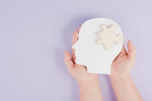 Holding a head with a puzzle piece, mental disease like Autism, Alzheimer, stroke awareness, brainstorming for ideas, memory problems