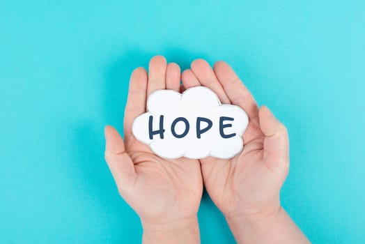 Holding a cloud with the word hope in the palm of the hands, trust and believe concept, having faith in the future, hopeful positive mindset