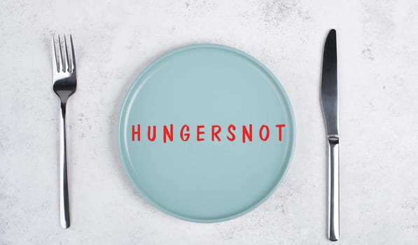 Famine is standing in german language on the plate, food shortage and starving because of the war and inflation, political issue