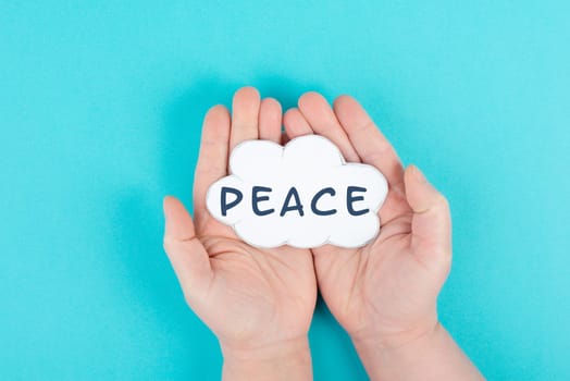 Holding a cloud with the word peace in the hands, stop war, support, living peaceful together