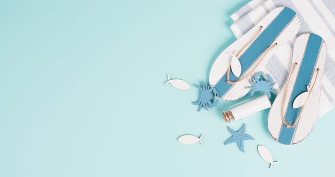 Blue colored summer and holiday background, flip flops, sea stars and a glass bootle with copy space, travel and tourism concept