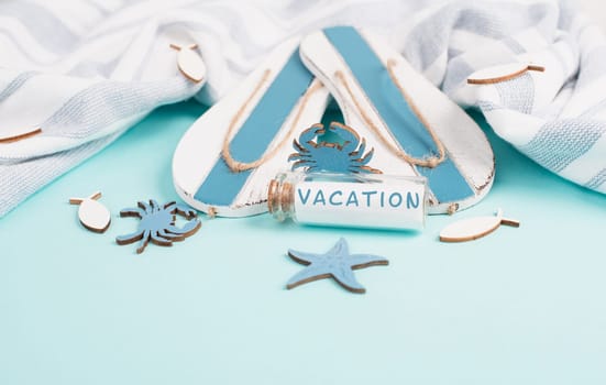 Blue colored summer and holiday background, flippers, sea stars and a glass bootle with the word vacation, travel and tourism concept
