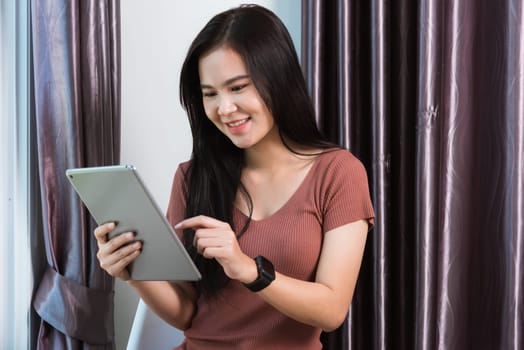 Work from home, Happy Asian young businesswoman smile video conference call or facetime by modern digital smart tablet computer she uses finger touching on screen, looking to tablet at home office