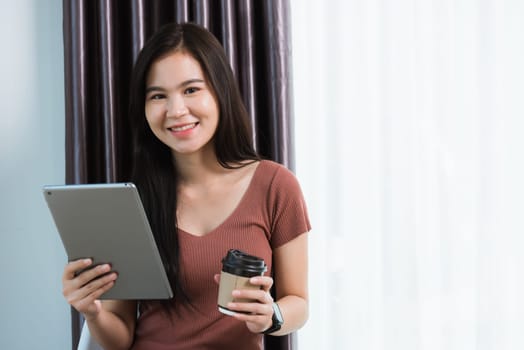 Work from home, Happy Asian young businesswoman smile video conference call or facetime by modern digital smart tablet computer she uses finger touching on screen, looking to camera at the home office