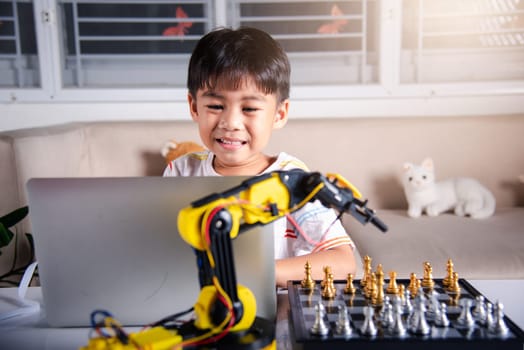 Asian little boy programming code to robot machine arm on laptop for play chess, STEM education E-learning, Funny children learning getting lesson control robot arm, Technology science education