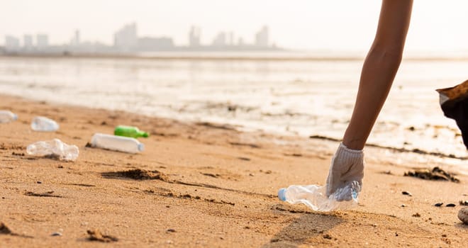 Volunteer woman picking plastic bottle into trash plastic bag black for cleaning the beach, female clean up garbage, Ecology concept and World Environment Day, Save earth concept