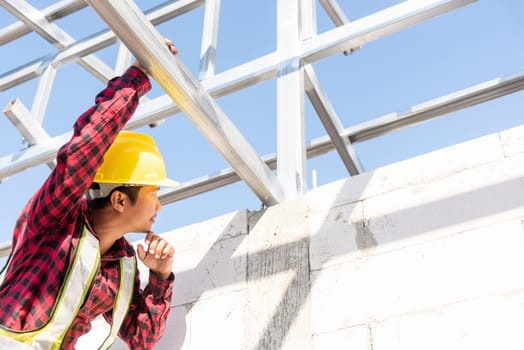 Construction worker or contractor checking house frame, worker roofer builder working on steel roof structure on building  construction site