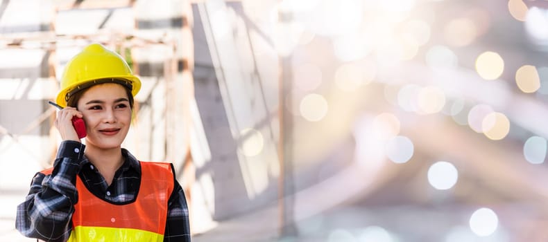 Asian engineer foreman architect worker woman working at building construction site talking with radio, engineering hold radio discuss operate and control worker employee to building construction
