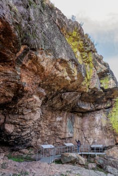 Visitor at Chiquita Cave, rock shelter with prehistorical paintings at Villuercas geopark. Canamero, Caceres, Extremadura, Spain