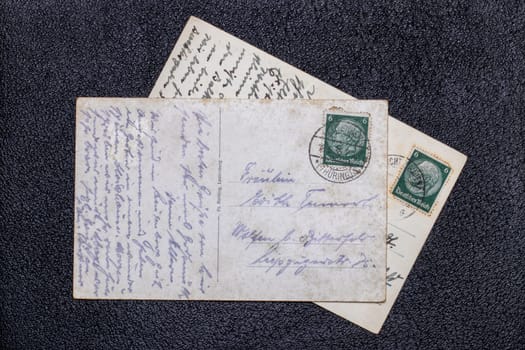 Potsdam, Germany - MAY 06, 2022. Old postcards from 1935 and 1939 with stamps showing the portrait of the German Reich President Paul von Hindenburg, Germany, Third Reich. Black background.