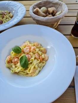 Plate of delicious pasta with shrimps on white wooden table, top view