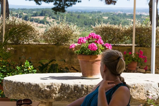 Woman sitting in outdoor cafe in background pine forests and mountains
