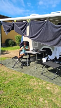 Man sits in front of his camper in a deck chair and relaxes