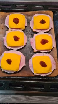 Open faced sandwiches with fried chicken breast and fried onions with pineapple and cheese on a baking sheet