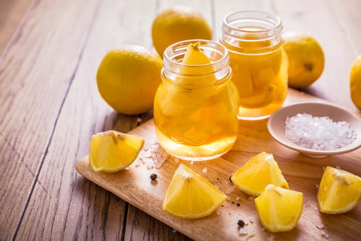 Preserved, salted canned lemons, lemon pickle on wooden background. Moroccan cuisine