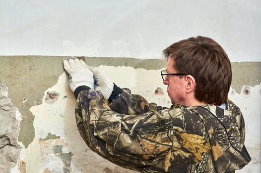 removing paint from the wall with a scraper, repairing the room. High quality photo