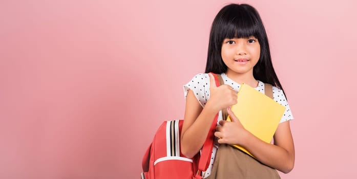 Asian little kid 10 years old with backpack is staying ready for back to school at studio shot isolated on white background, Portrait of happy child girl with school bag and holding or hugging books