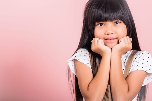 Asian little kid 10 years old hands touch chin thinking dream at studio shot isolated on pink background, Portrait of Happy child girl positive smiling rejoices good day with lover
