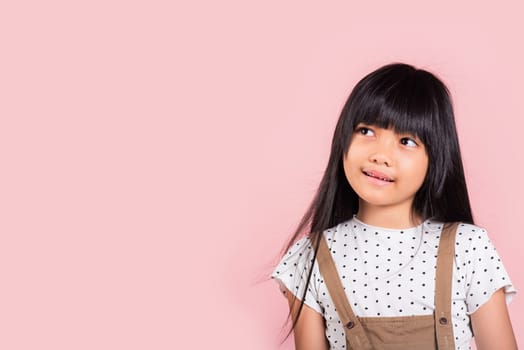 Asian little kid 10 years old looking away to side natural expression at studio shot isolated on pink background, Portrait of Happy child girl smiling staring away thinking