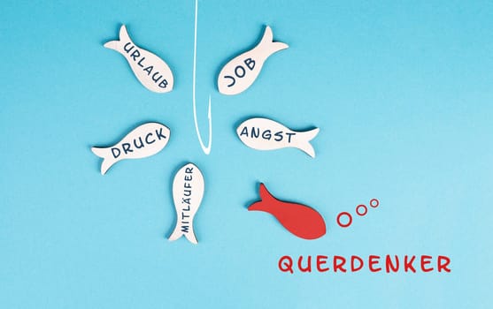 Group of fishes with words like fear, pressure, follower swimming to the fishing rod, red fish makes his own decision, takes a different direction, against the stream, german language