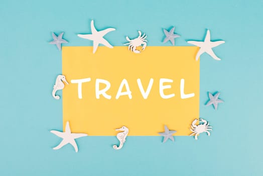 The word travel is standing on a yellow colored paper, sea stars, seahorses and crab bulding a frame, summer vacation, tourism destination