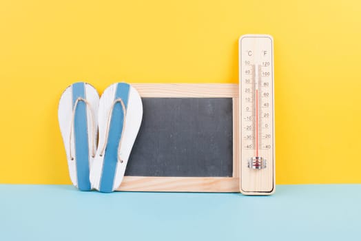 Empty chalkboard with a thermometer and flip flops, holiday background, summer vacation, hot weather, environmental issue
