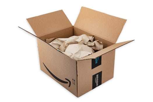 WETZLAR, GERMANY 2022-04-25: Amazon Prime cardboard box open with wrapping paper on white background. Prime is a service offered by online retailer Amazon for faster delivery of orders.