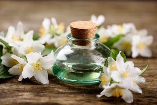 Aromatic oil with jasmine flower on rustic wooden table
