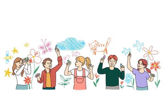 Diverse smiling small kids have fun drawing on white wall with chalks and pencils together. Happy boys and girls children enjoy leisure activity involved in painting. Art and hobby concept.