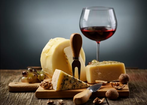 Cheese and red wine on wooden board.