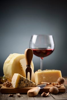 Cheese and red wine on wooden board.