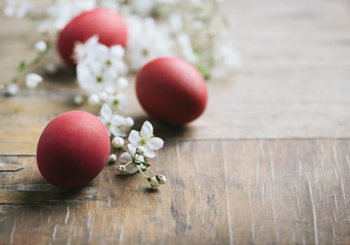 Red easter eggs and spring blossom on rustic wooden table