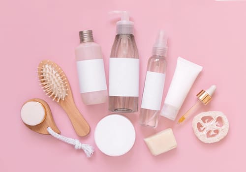 Homemade organic cosmetics in tubes and bottles and eco friendly accessories on pink flat lay, copy space. Top view of natural beauty products for hair and skin care