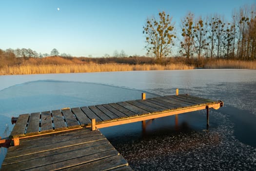 Wooden pier and a frozen lake on a winter evening, Stankow, Poland