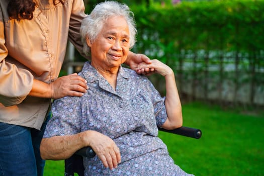 Caregiver help Asian elderly woman disability patient sitting on wheelchair in park, medical concept.