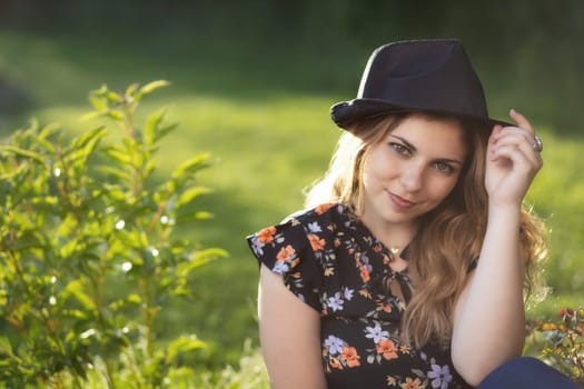 Portrait of attractive  young woman in black  straw hat posing outdoors in summer day. Horizontally.